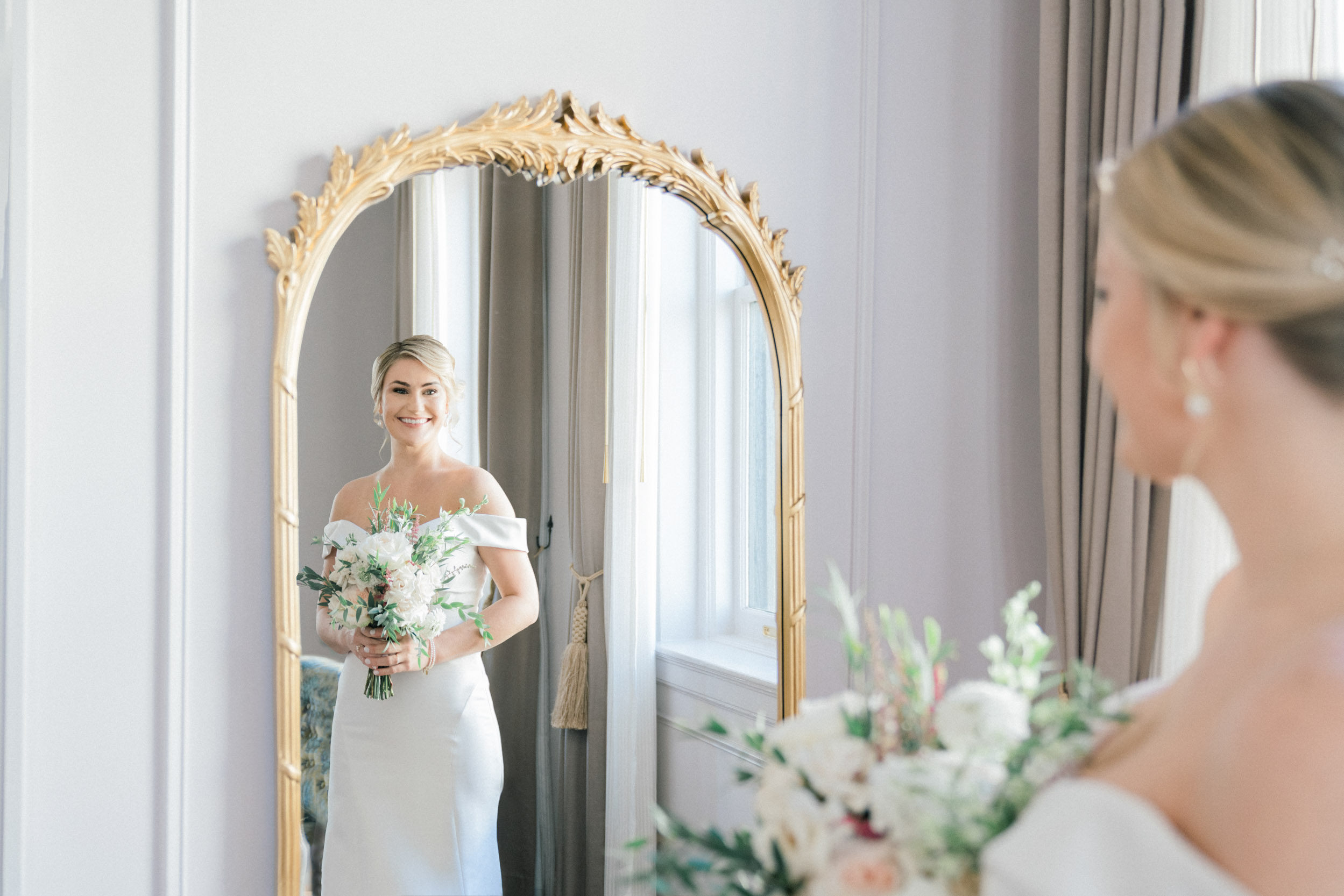 bride looking in mirror with flowers on wedding day at the Maison De La Luz Hotel in New Orleans