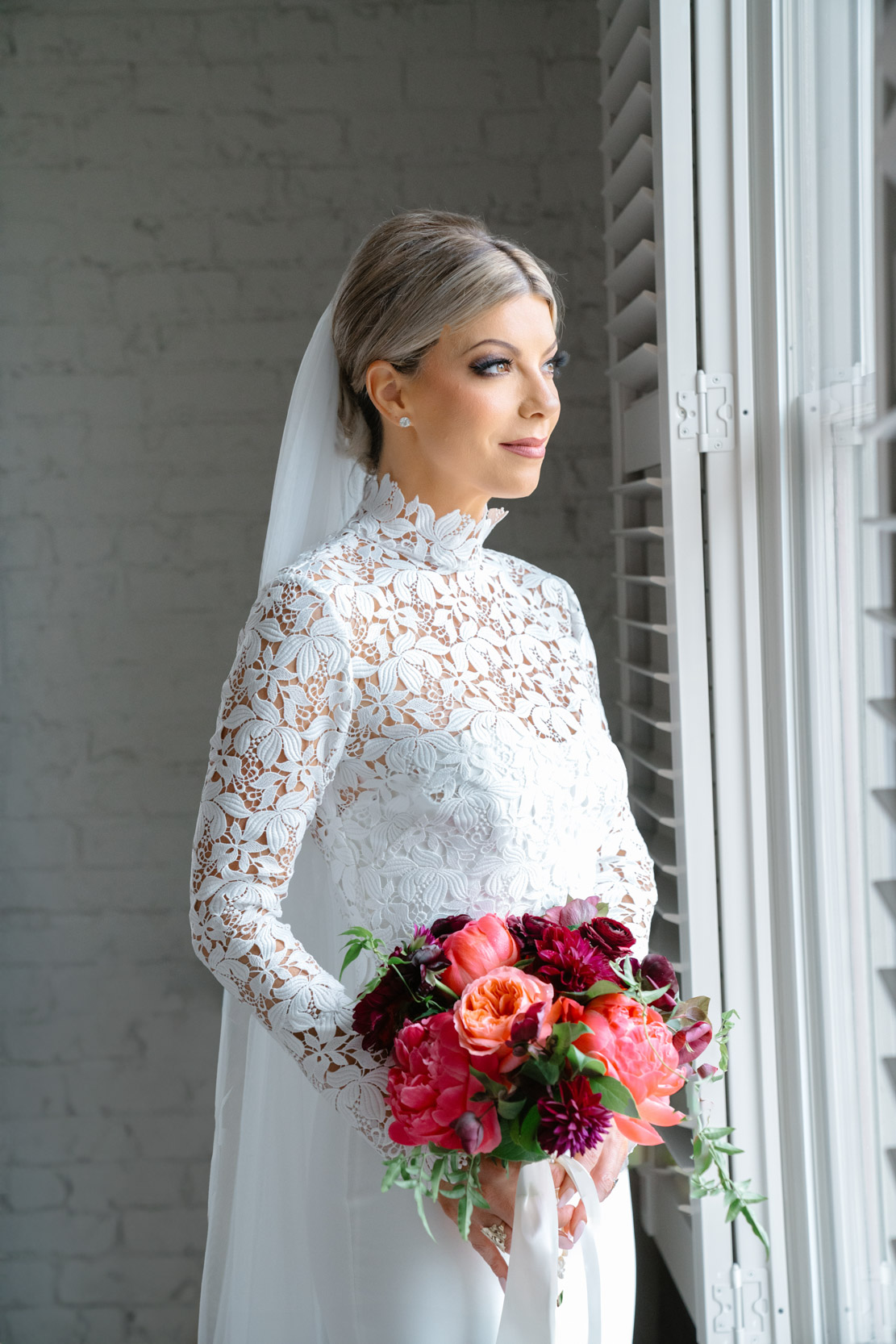 bride looking out window holding Petals and Parties flowers at the Southern Hotel in Covington, Louisiana