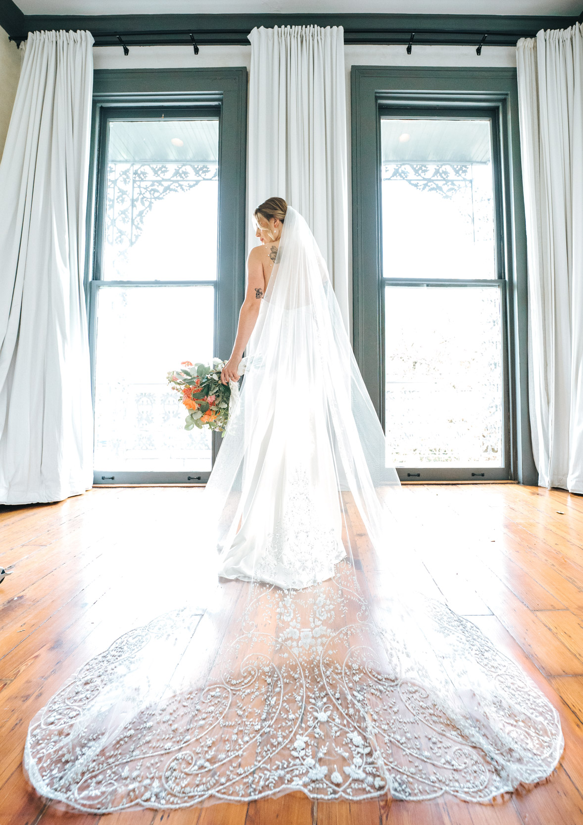 bride posing in front of windows with wedding dress train on hard wood floor at Margaret Place in New Orleans