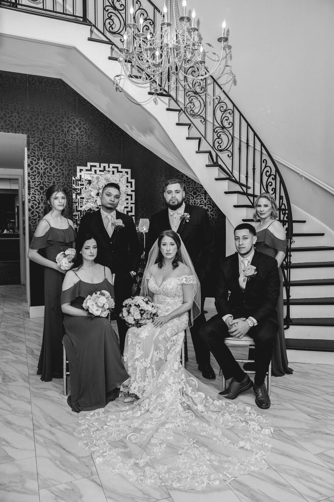 family sitting and posing for family photos on marble floor under chandelier at The Pearl Room in Harahan, Louisiana