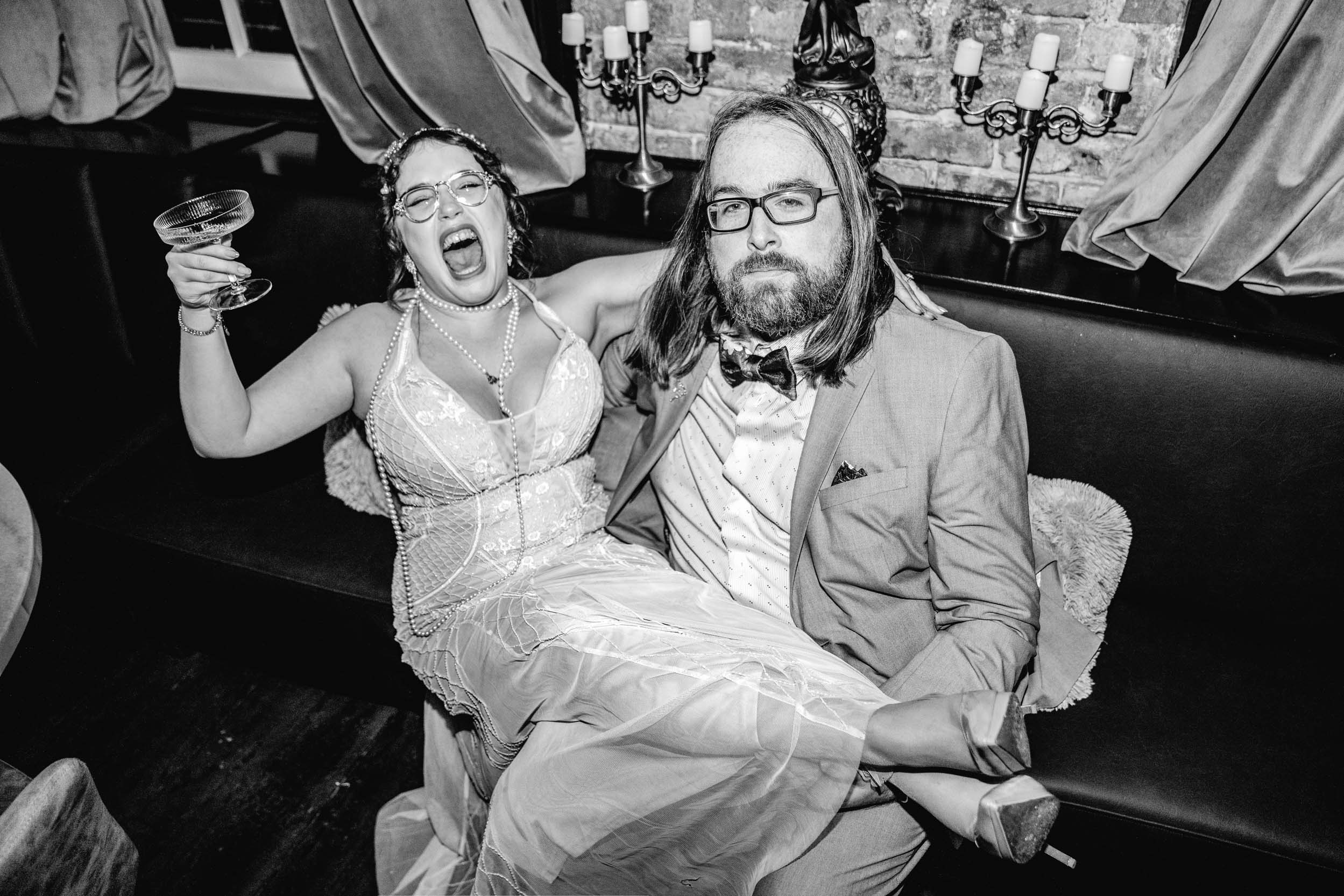 flash photo of bride sitting in groom's lap laughing and drinking champagne at the Historic Swoop Duggins House in New Orleans