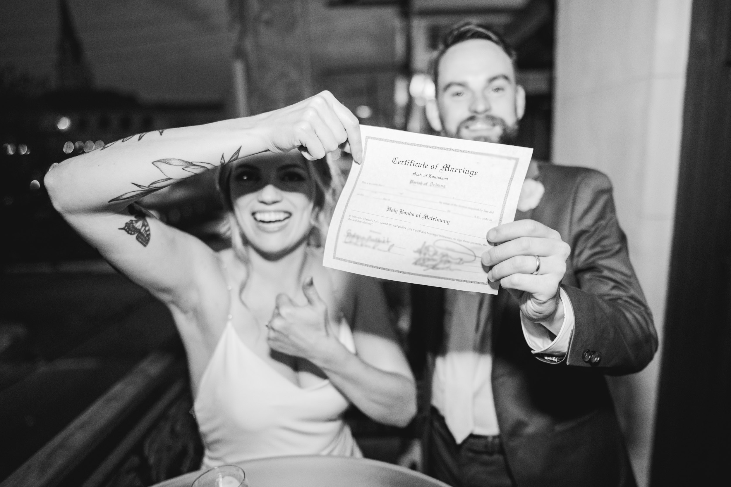 flash photograph of bride and groom holding up their marriage license and smiling at Margaret Place in New Orleans