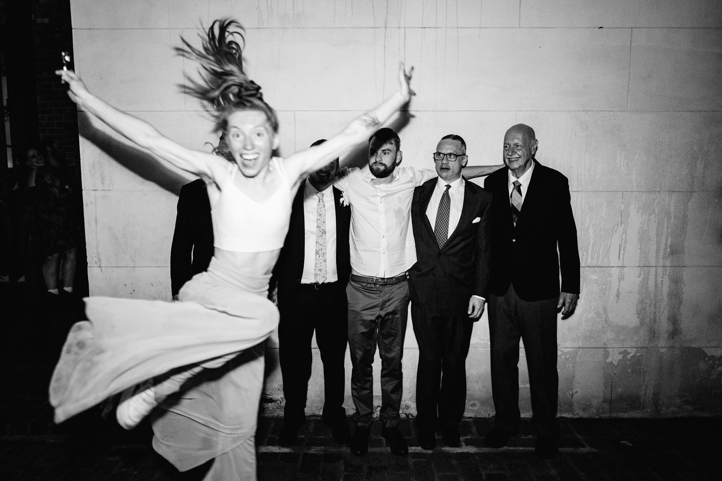 girl jumping out in front of men posing for a photo at Margaret Place in New Orleans