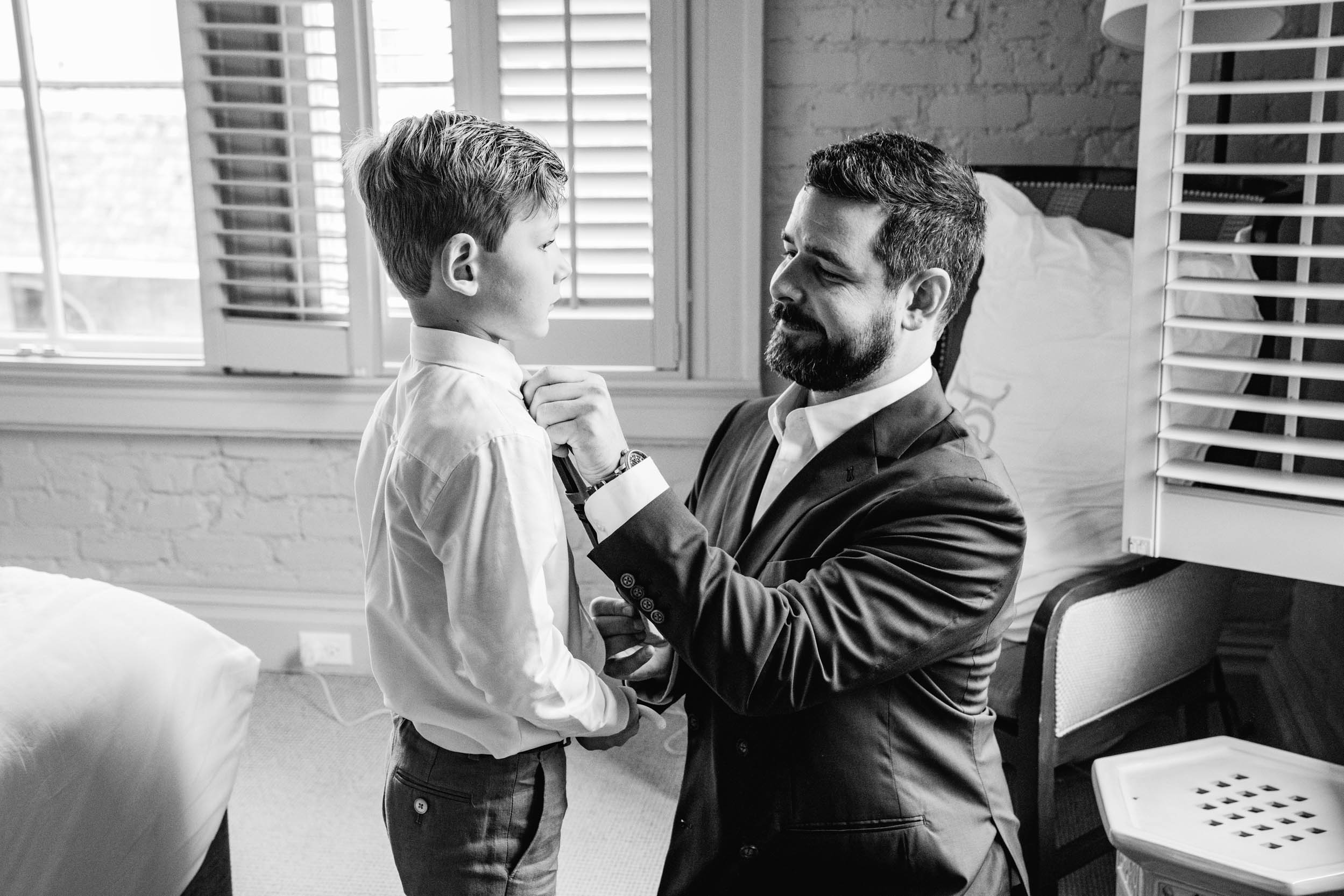 groom adjusting his son's tie on wedding day at the Southern Hotel in Covington, Louisiana