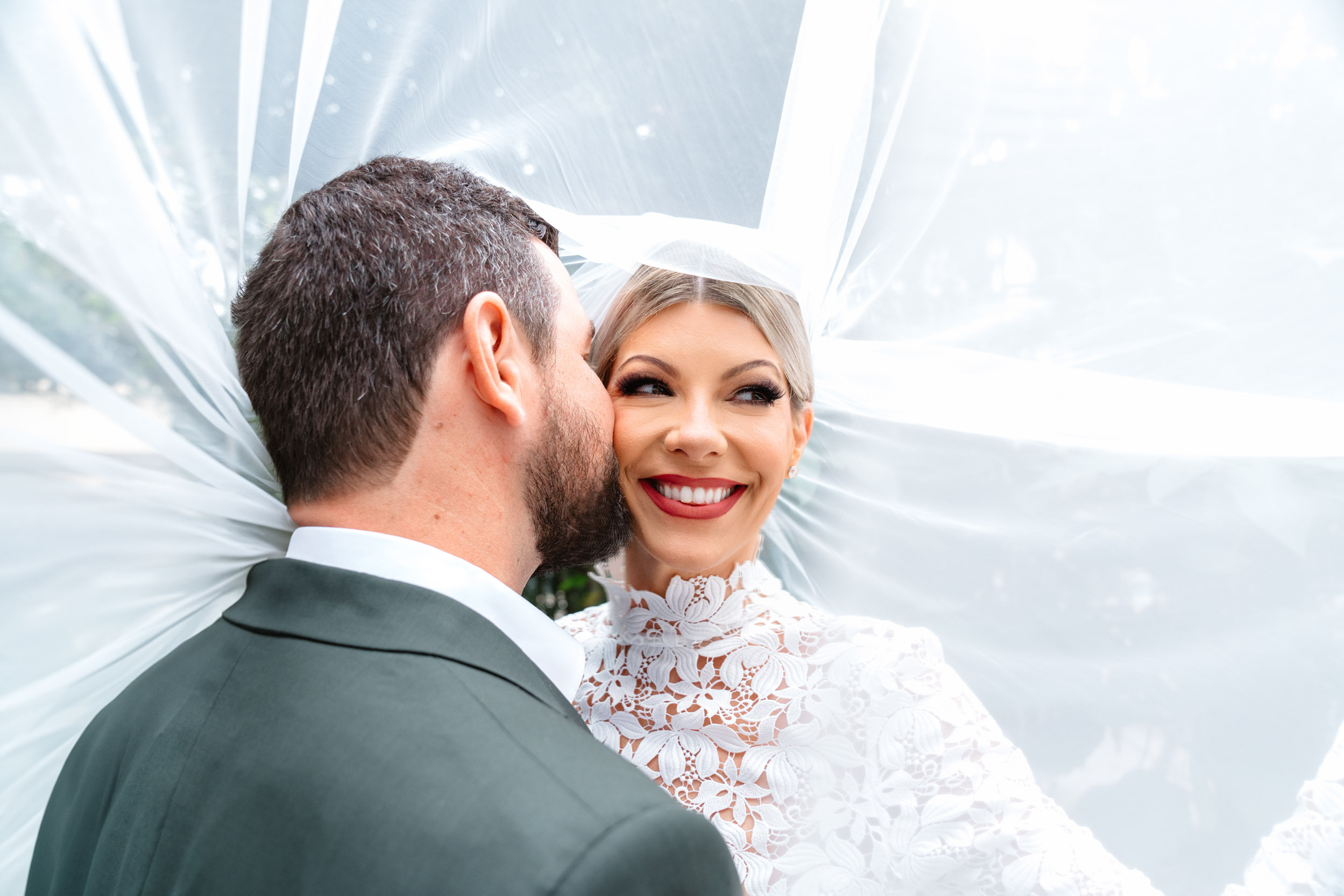 groom kissing bride while smiling under her veil at the Southern Hotel in Covington, Louisiana