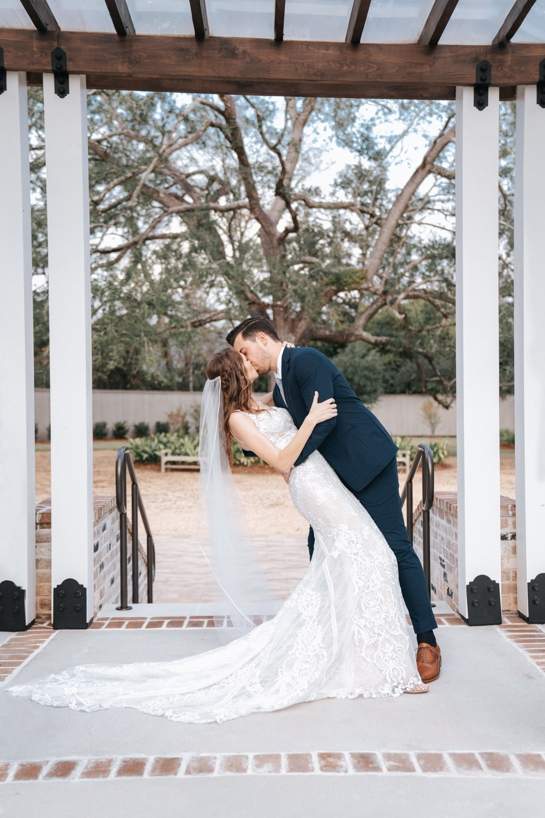 groom leaning over his bride and kissing her at First Baptist Church on wedding day in Covington, Louisiana