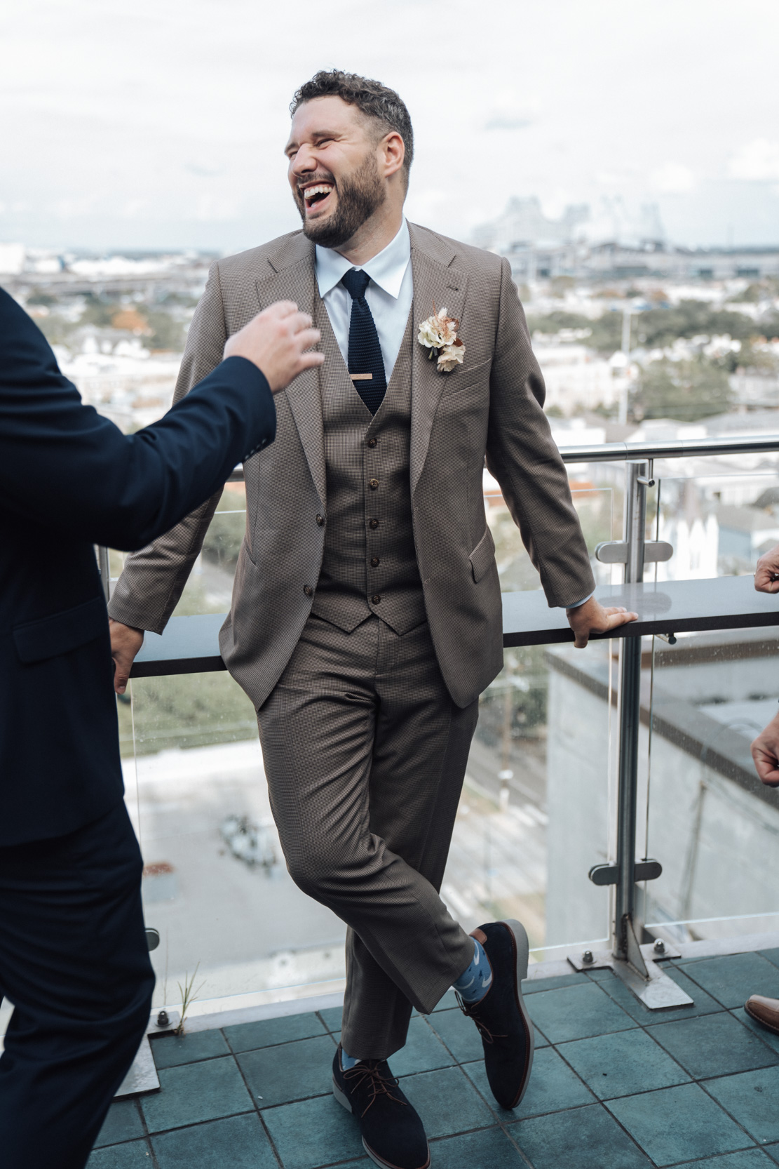 groom wearing beige tweed suit on wedding day on the rooftop of the The Pontchartrain Hotel in New Orleans