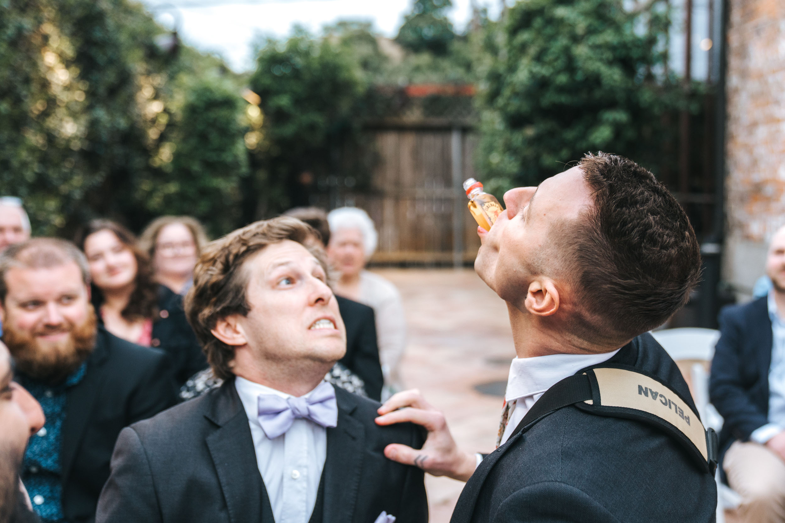 groomsmen pouring Fireball shots and baby-birding Fireball into each others mouths during wedding ceremony at Rosy’s Jazz Hall in New Orleans