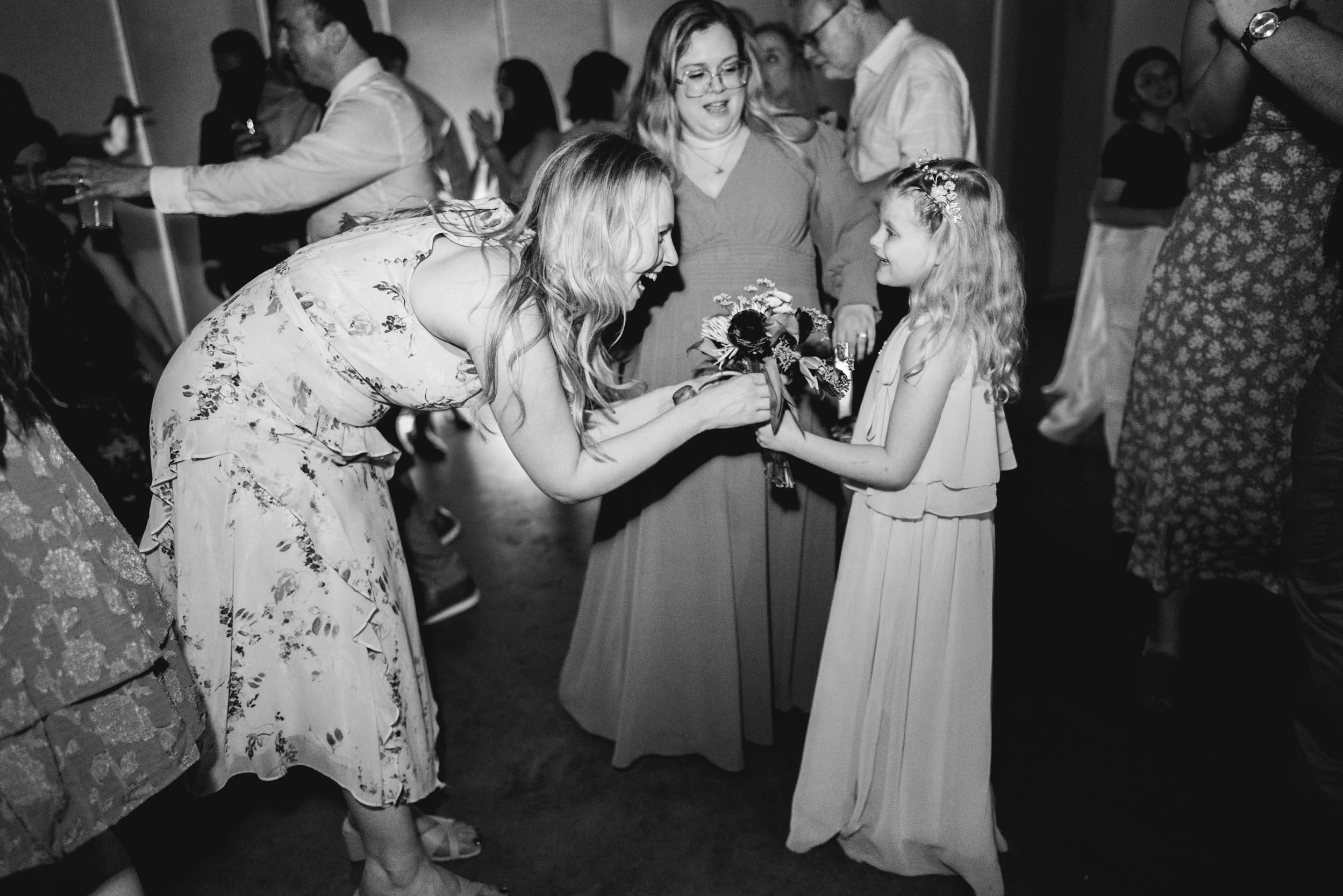 lady handing bridal flowers to little girl during wedding reception at Capulet in the New Orleans Bywater