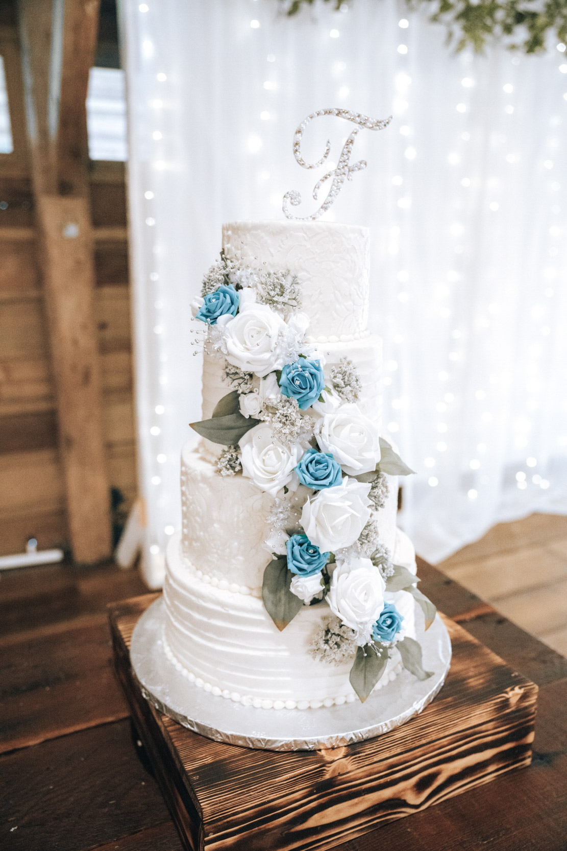 wedding cake with blue and white roses on rustic table at Destrehan Plantation in Louisiana