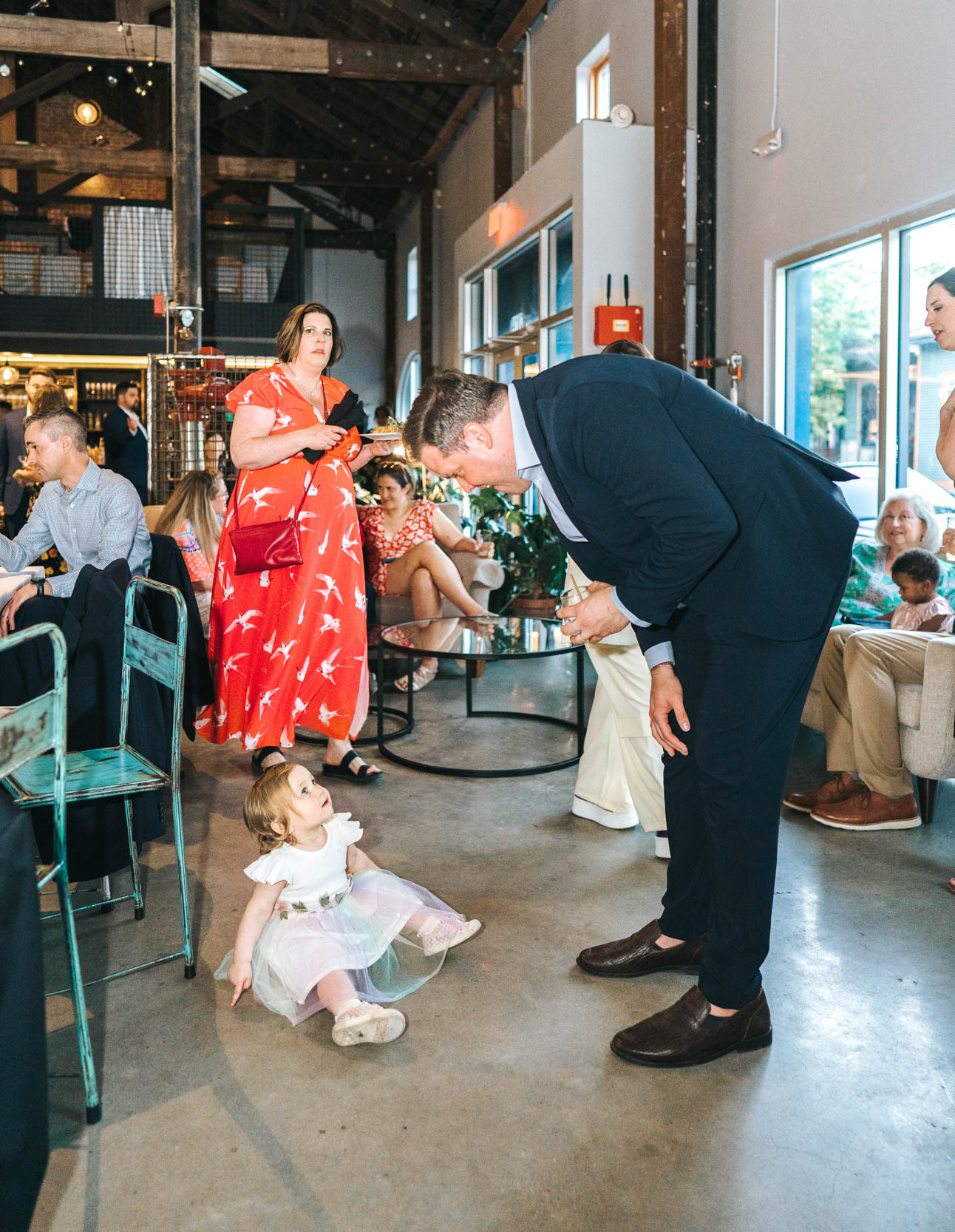 wedding guest looking down and admiring baby on the ground at Capulet in the Bywater New Orleans