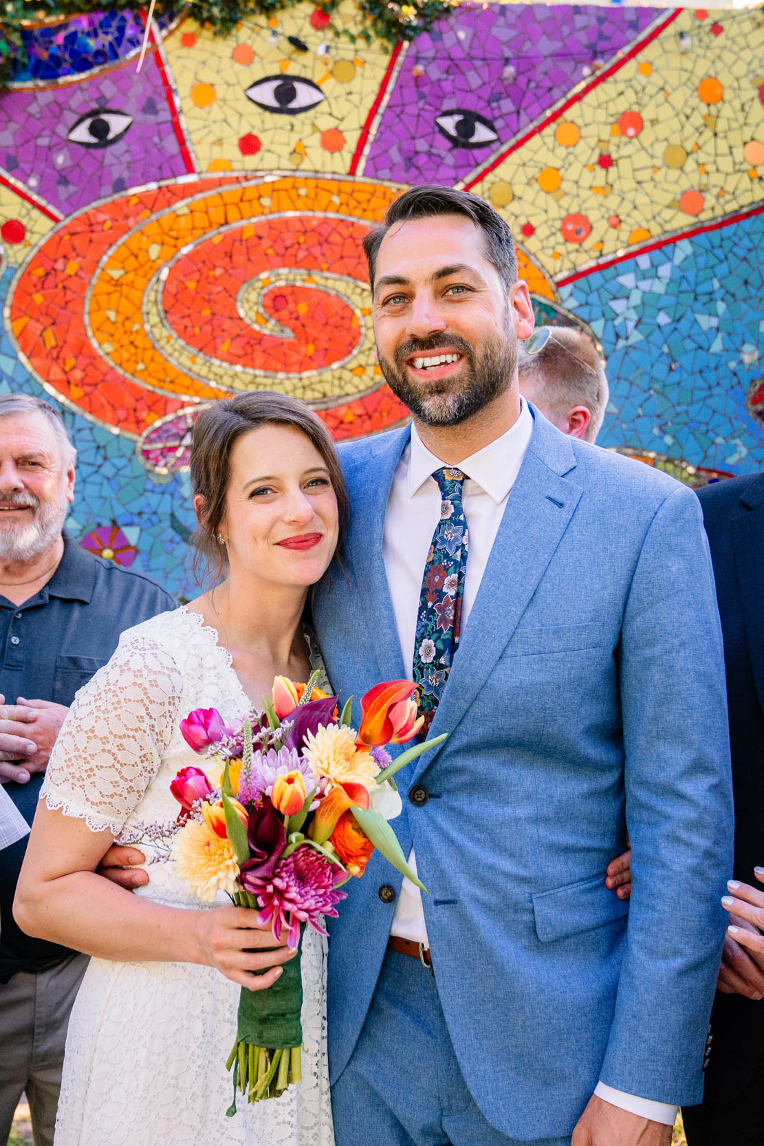 bride and groom smiling on their wedding day in front of colorful mural at at Clouet Gardens in the Bywater of New Orleans