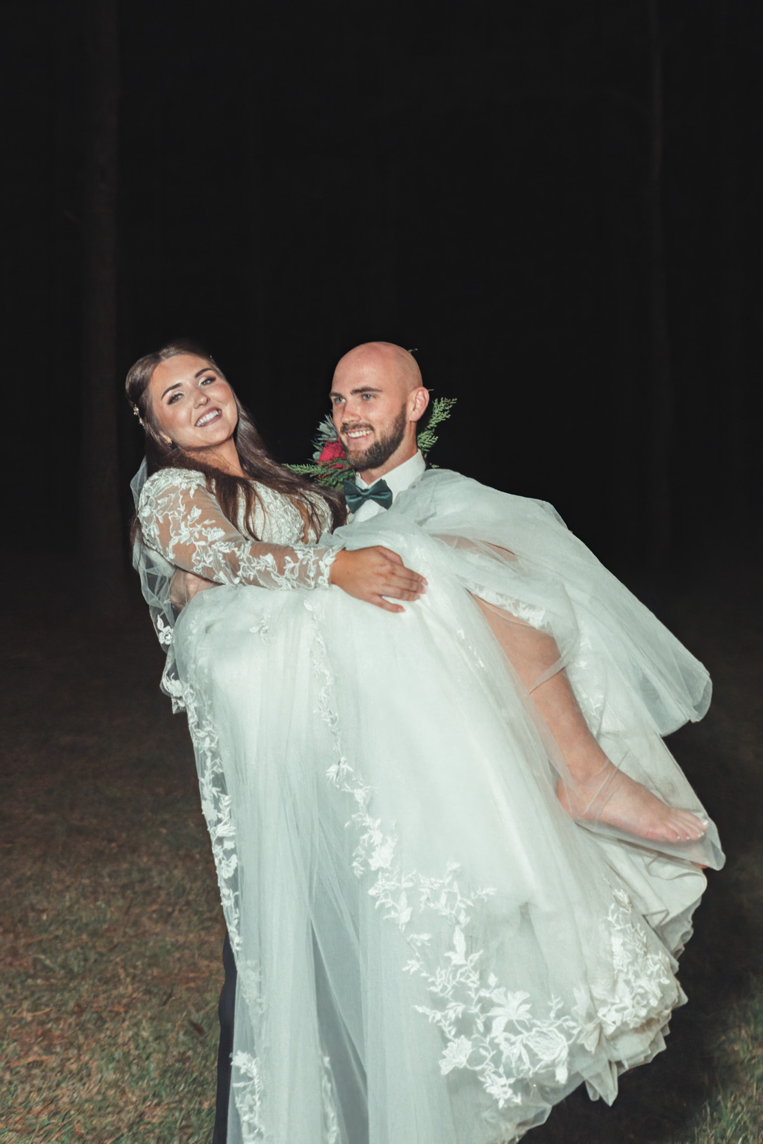 flash film photo of groom carrying bride at night at Creekview Barn in Mississippi