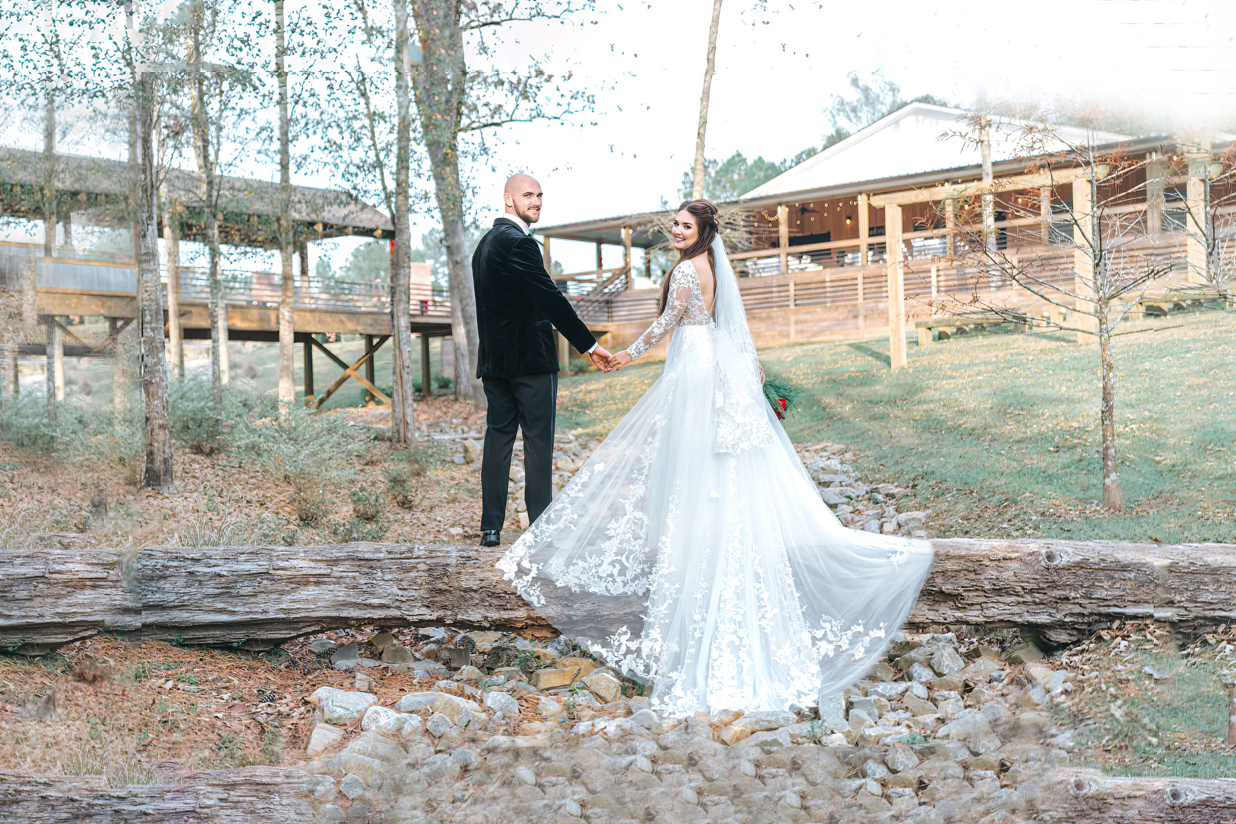 Bride and groom standing on log and creek at Creekview Barn in Mississippi