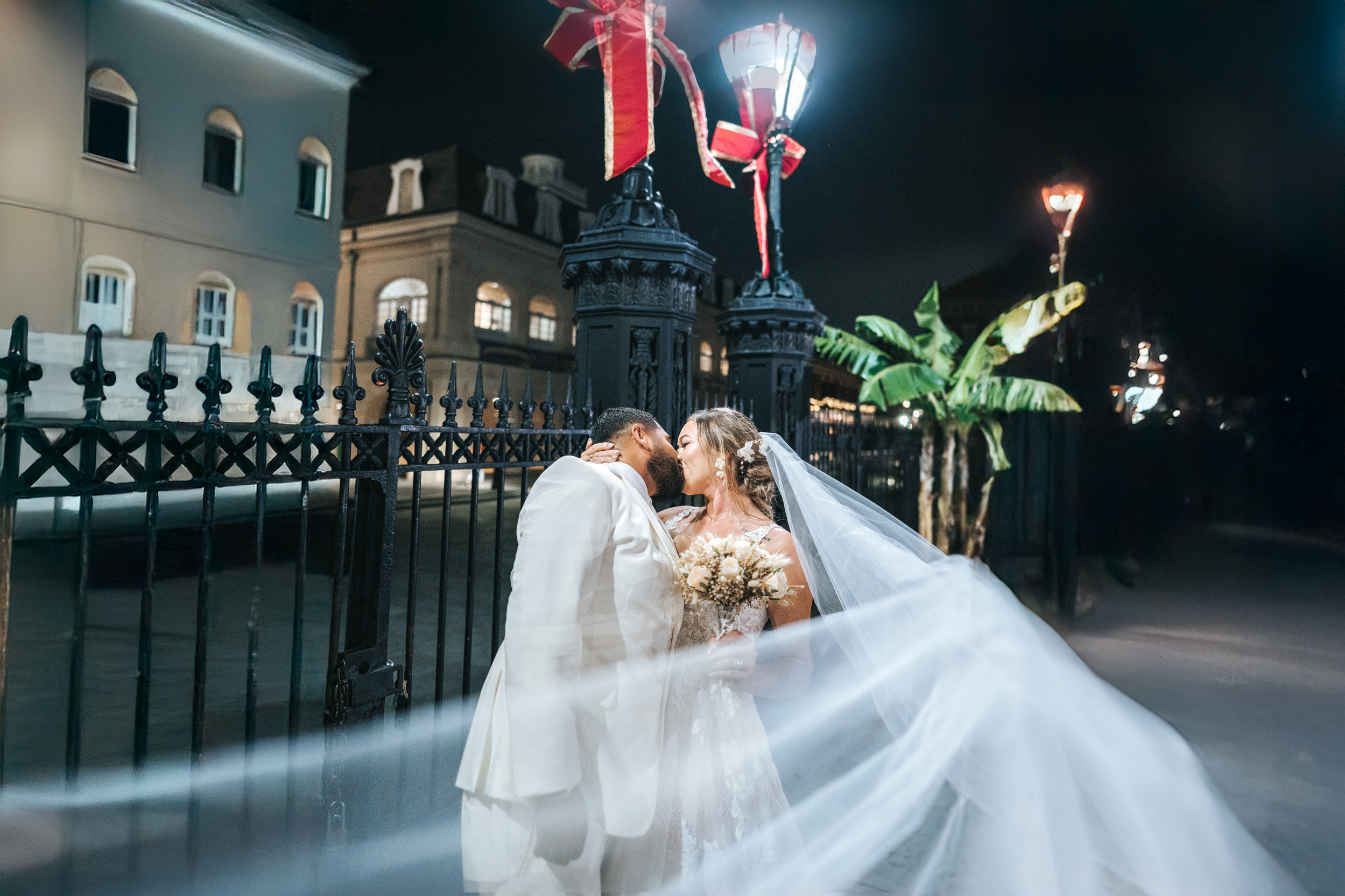 Bridal veil flying in the air and kissing groom at Jackson Square in New Orleans