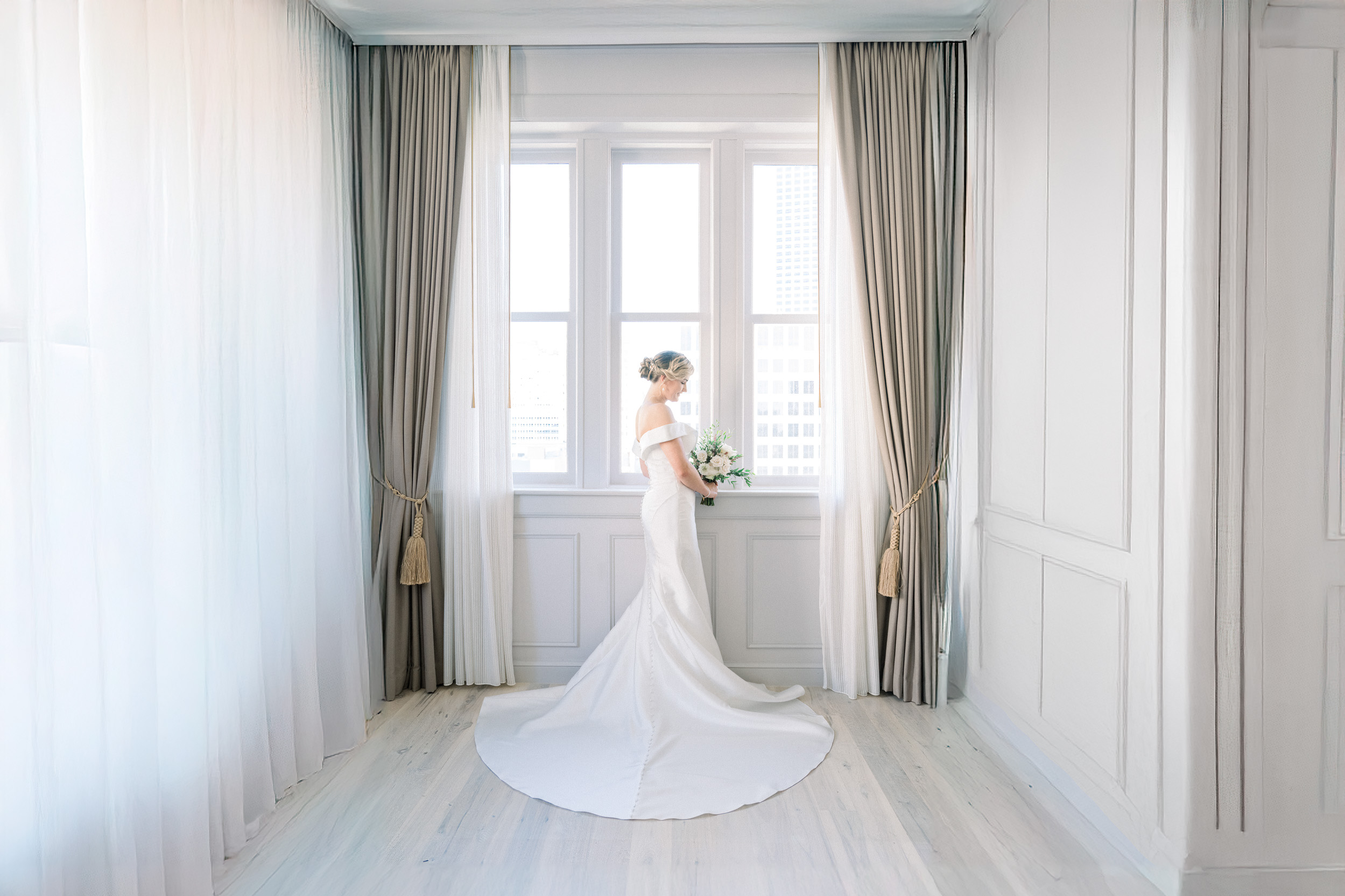 Bride gazing at flower bouquet in front of window at the Maison De La Luz Hotel in New Orleans