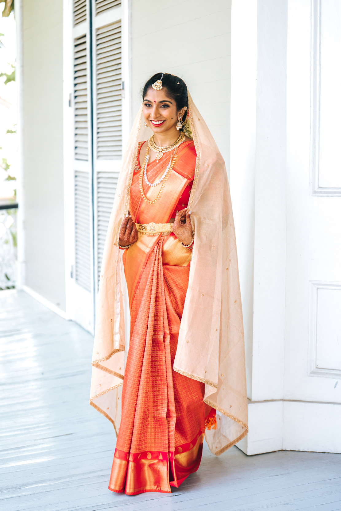 Islamic or Hindu American bride posing on balcony wearing lehenga and saree wedding dress before nikah ceremony at Derbès Mansion in New Orleans