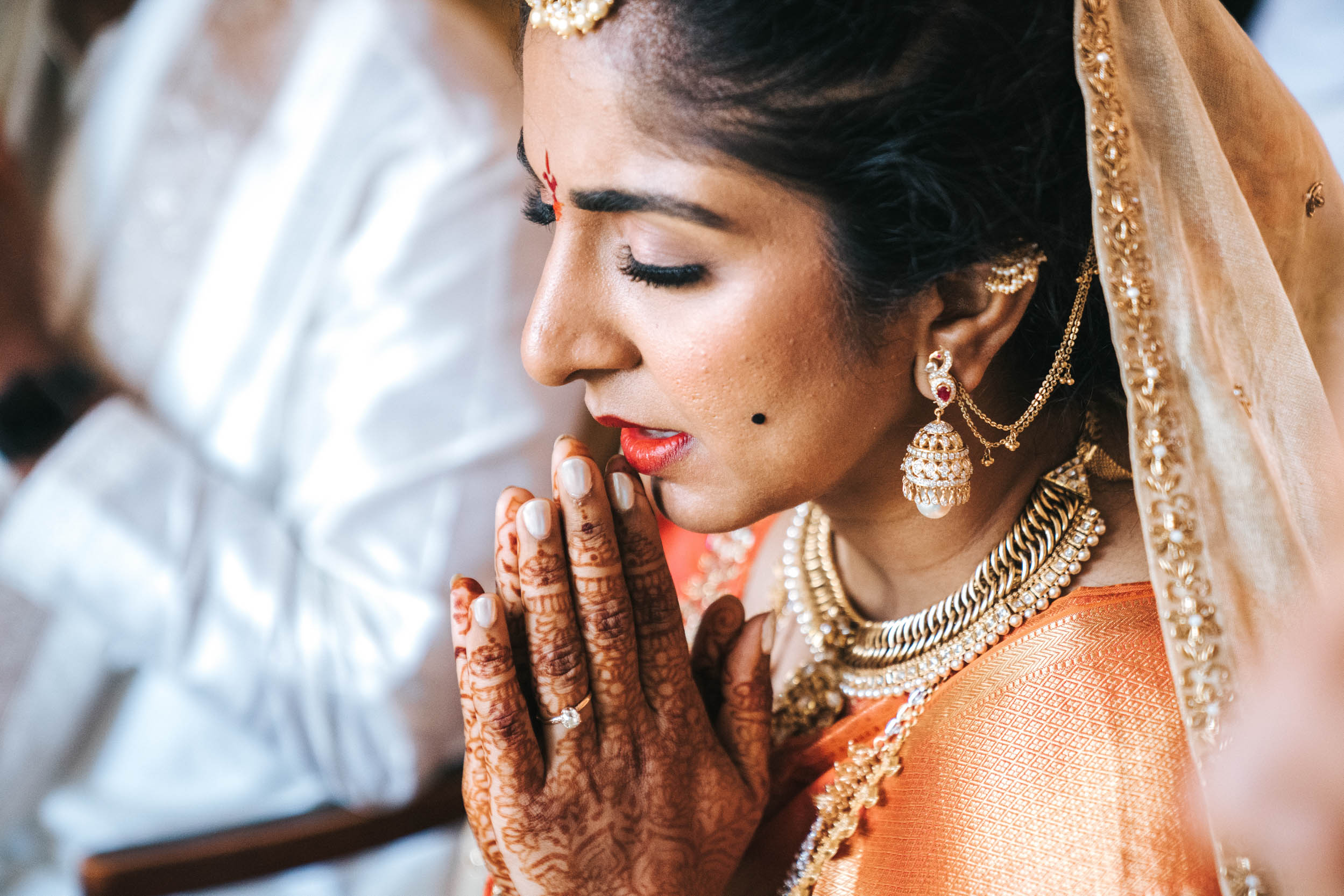 Islamic or Hindu American bride praying with henna on her hands before nikah ceremony at Derbès Mansion in New Orleans