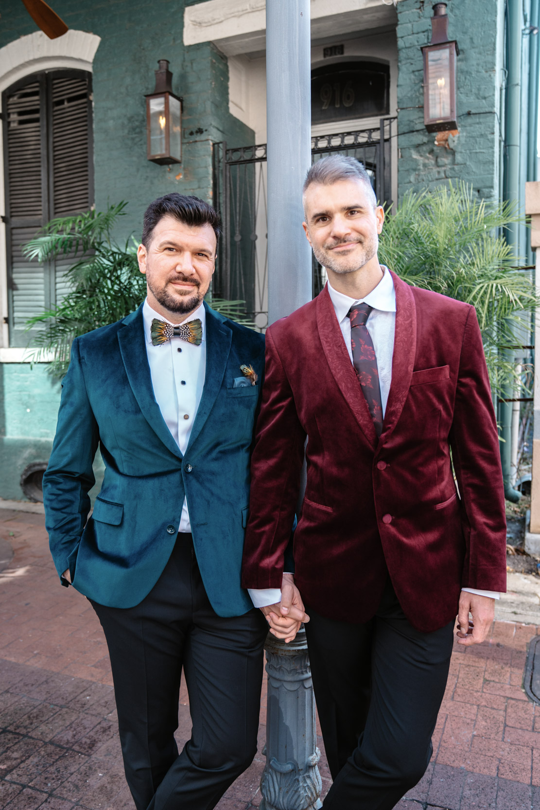 gay couple posing in green and red jackets on Bourbon Street in New Orleans on their wedding day