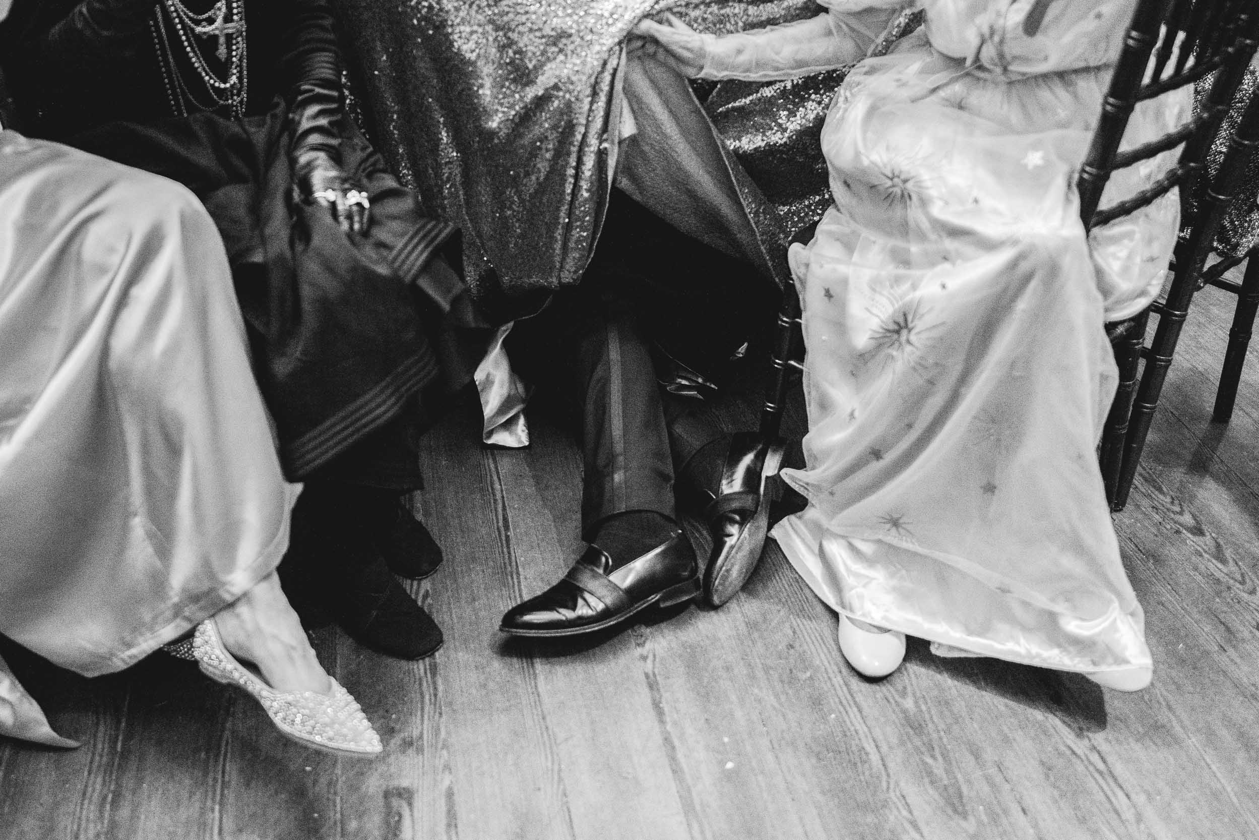 wedding guest hiding underneath table during wedding reception at Hotel Peter and Paul in New Orleans Bywater