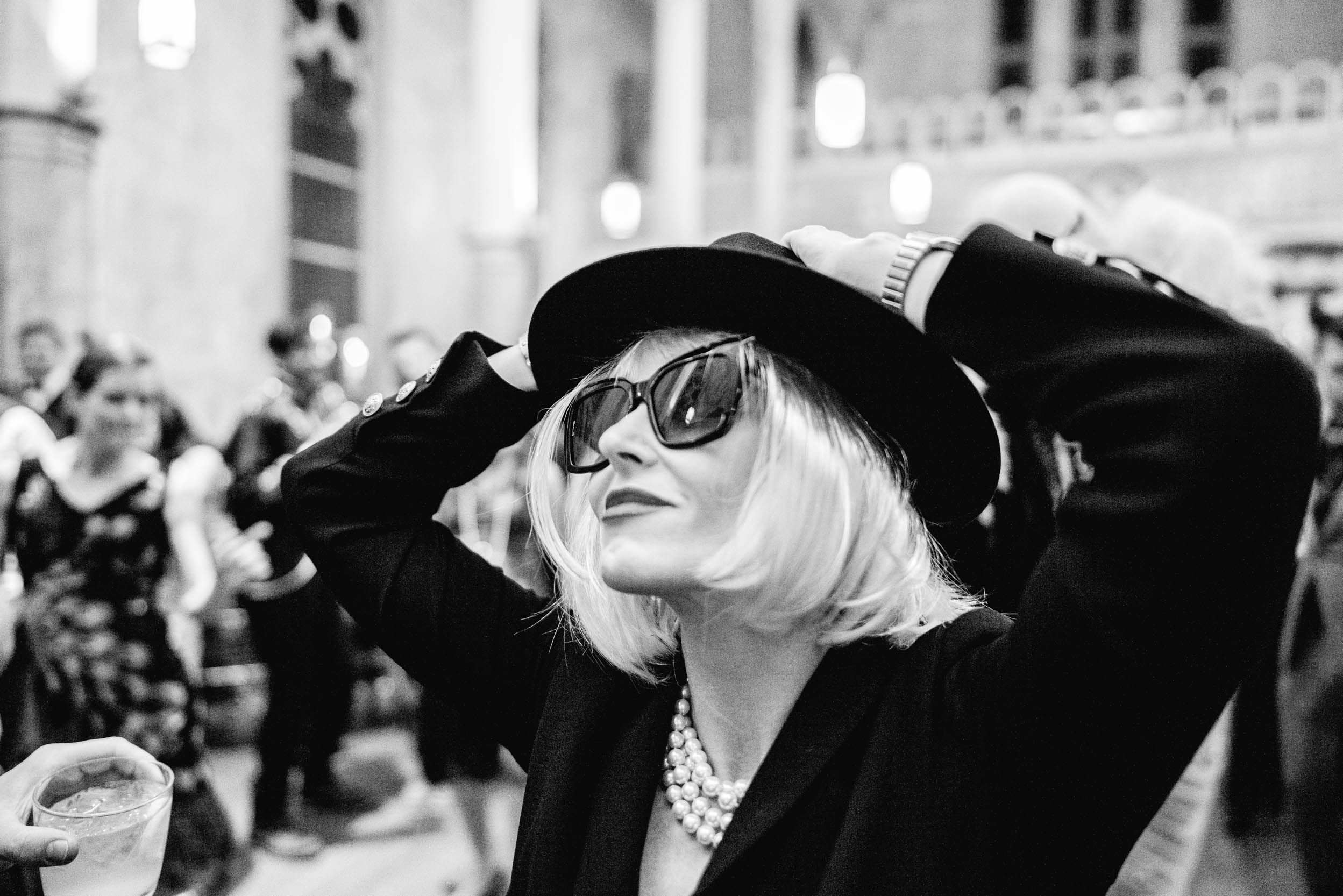 woman in all black with black glasses and black hat during masquerade wedding reception at Hotel Peter and Paul in New Orleans Bywater